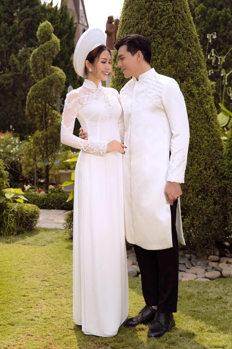 Cô dâu chú rể ôm eo nhau, áp sát gương mặt và trao ánh nhìn tình cảm khi tạo dáng chụp ảnh cưới trong khu vườn