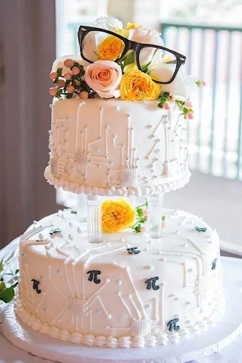 Bánh cưới hai tầng phong cách hiện đại, trang trí hoa tươi và họa tiết công nghệ độc đáo, tạo điểm nhấn ấn tượng cho tiệc cưới.