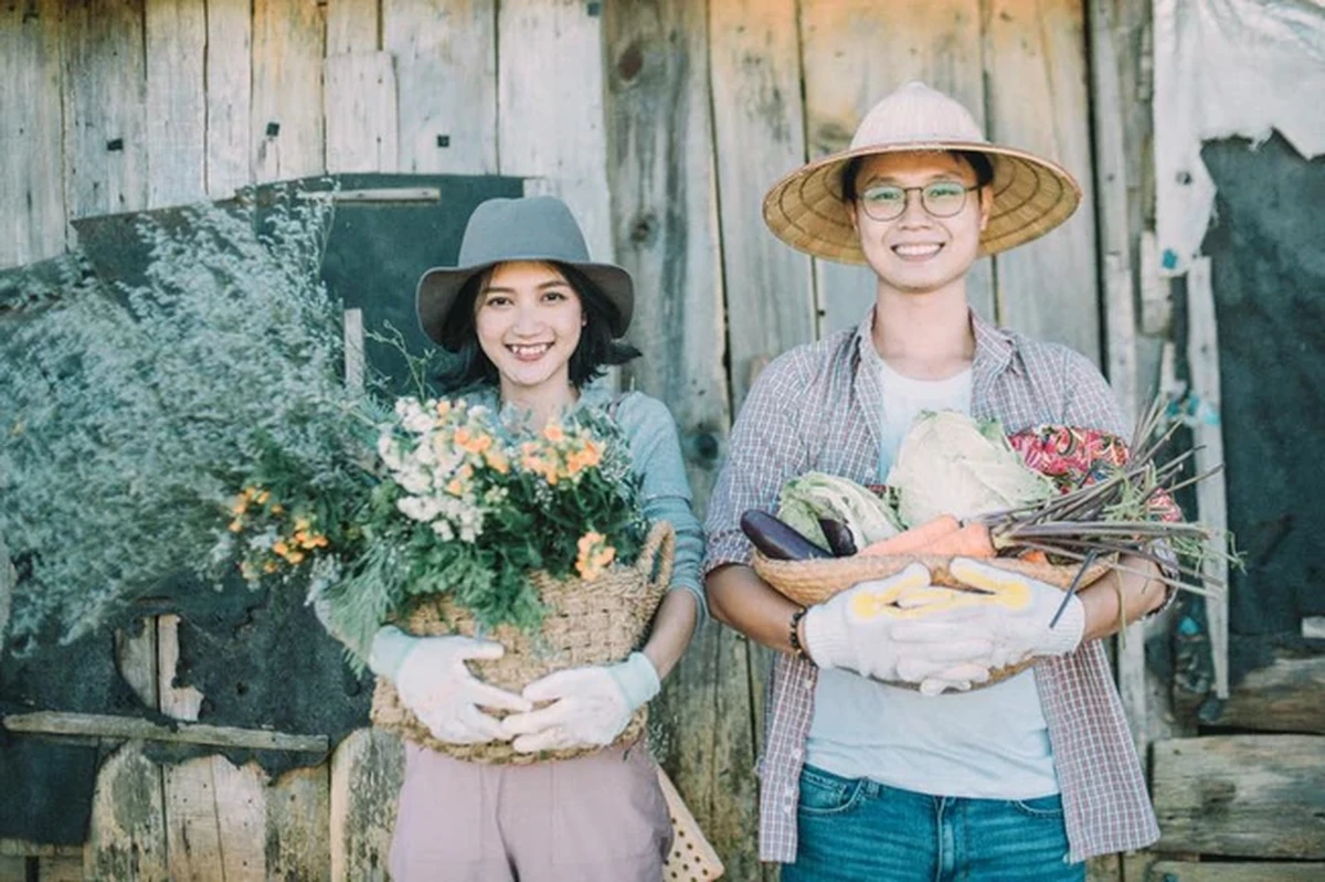 Cả 2 vui vẻ đứng cạnh nhau, trên tay là giỏ hoa và rau củ