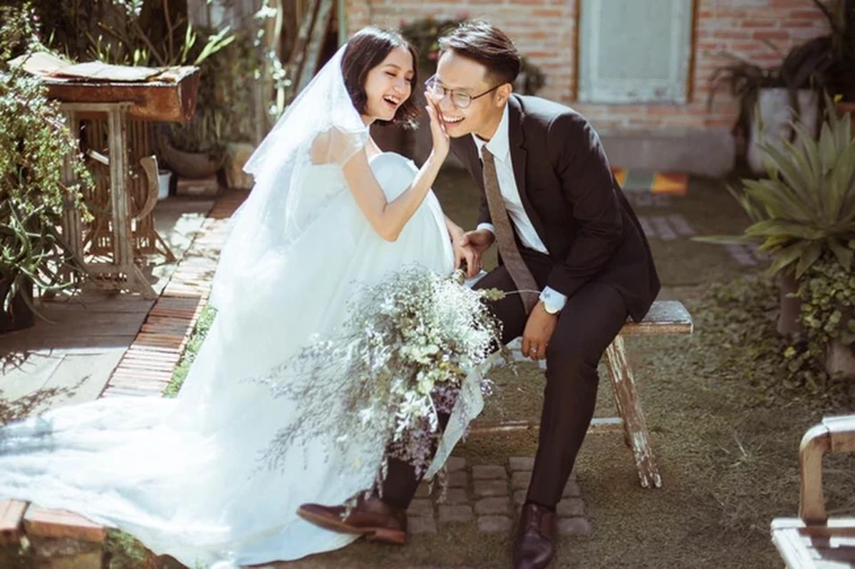 Cô dâu mắc váy cưới trắng cười vui vẻ bên chú rể