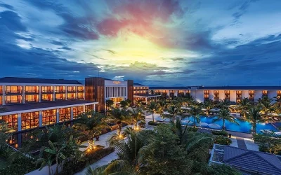 Khu nghỉ dưỡng biển cao cấp với hồ bơi ngoài trời, hàng dừa xanh và khung cảnh hoàng hôn ấn tượng