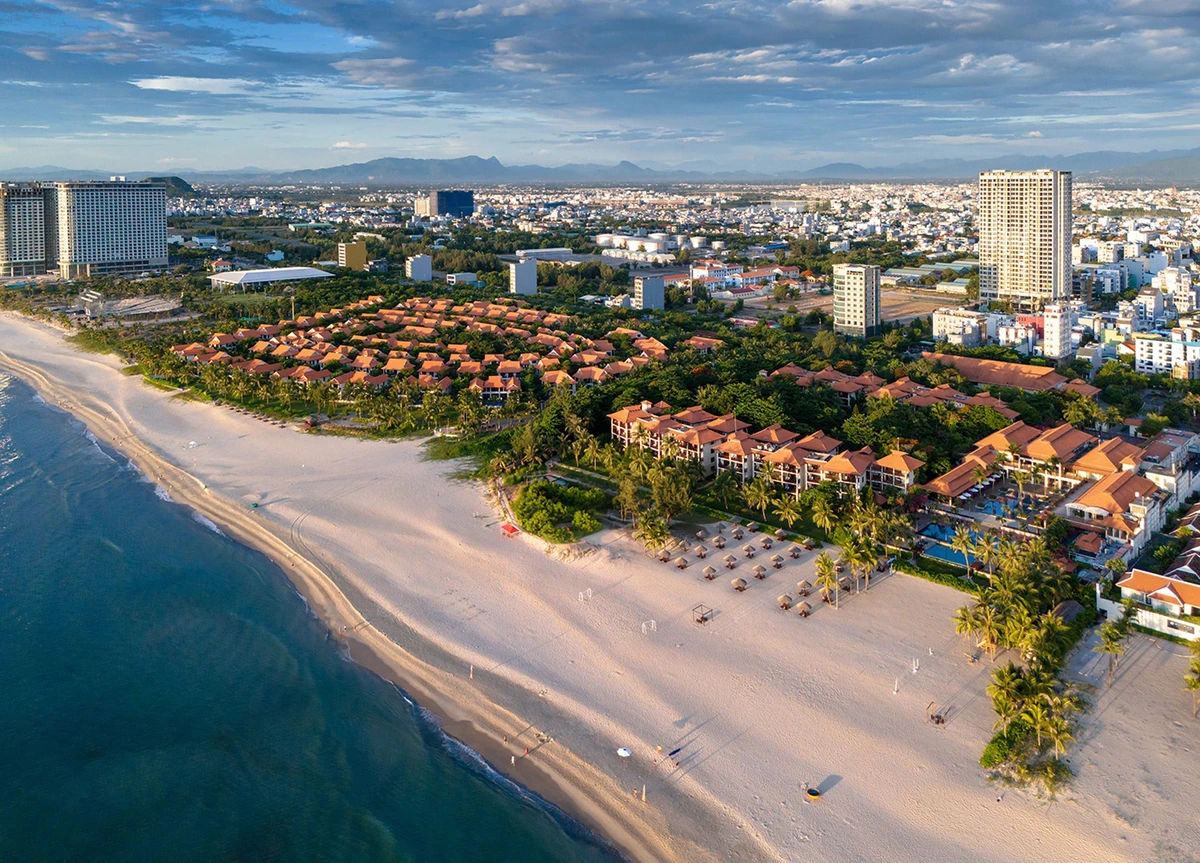 Toàn cảnh khu resort ven biển với bãi cát trắng, hàng dừa và khu nghỉ dưỡng sát bờ biển