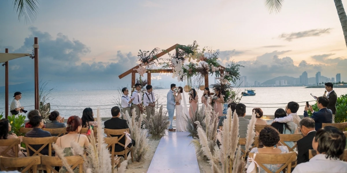 Lễ cưới ngoài trời ở bãi biển và có sân khấu hoa cùng khách mời