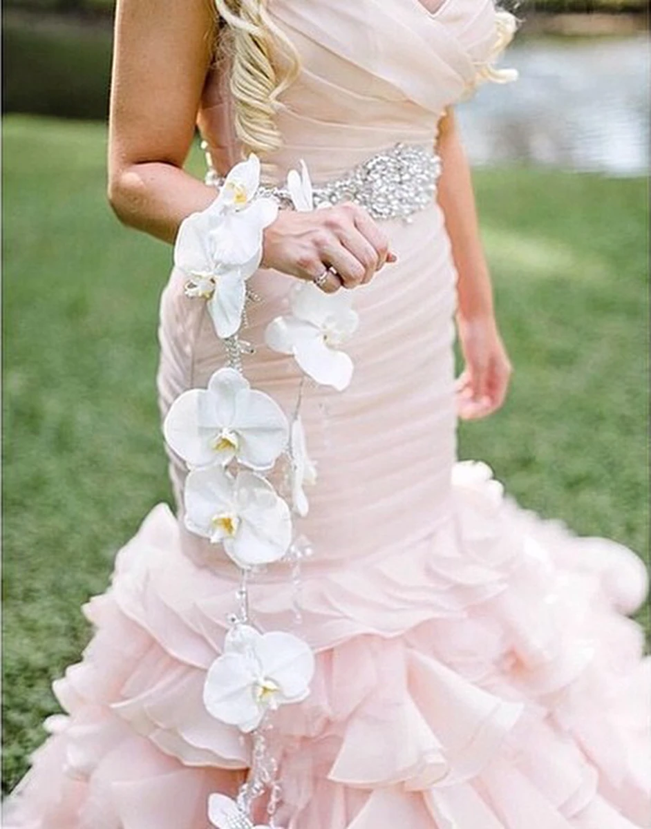 Cô dâu diện váy cưới phối cùng hoa cưới đeo tay màu hồng pastel