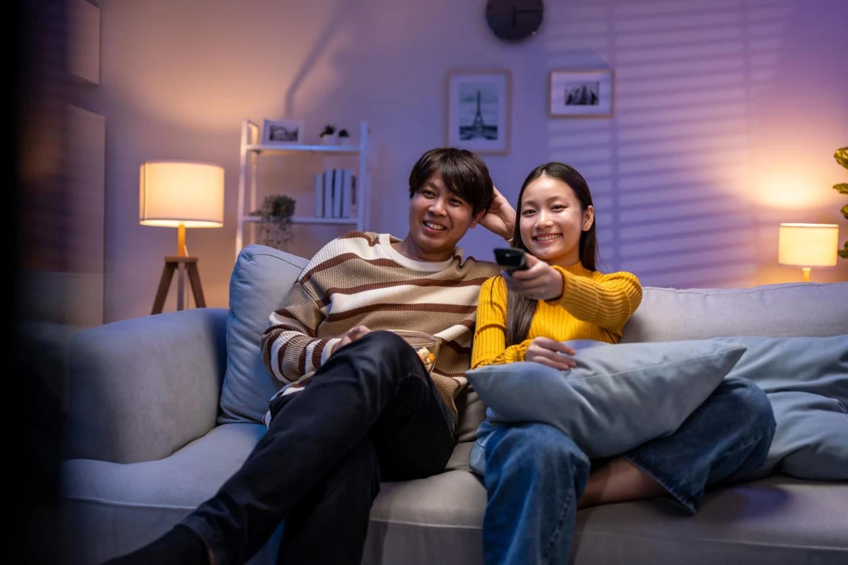Cặp đôi nam nữ đang ngồi ở sofa cười hạnh phúc