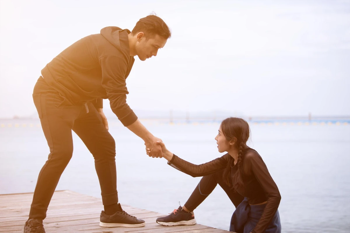 Người đàn ông đưa tay giúp đỡ người phụ nữ đứng lên