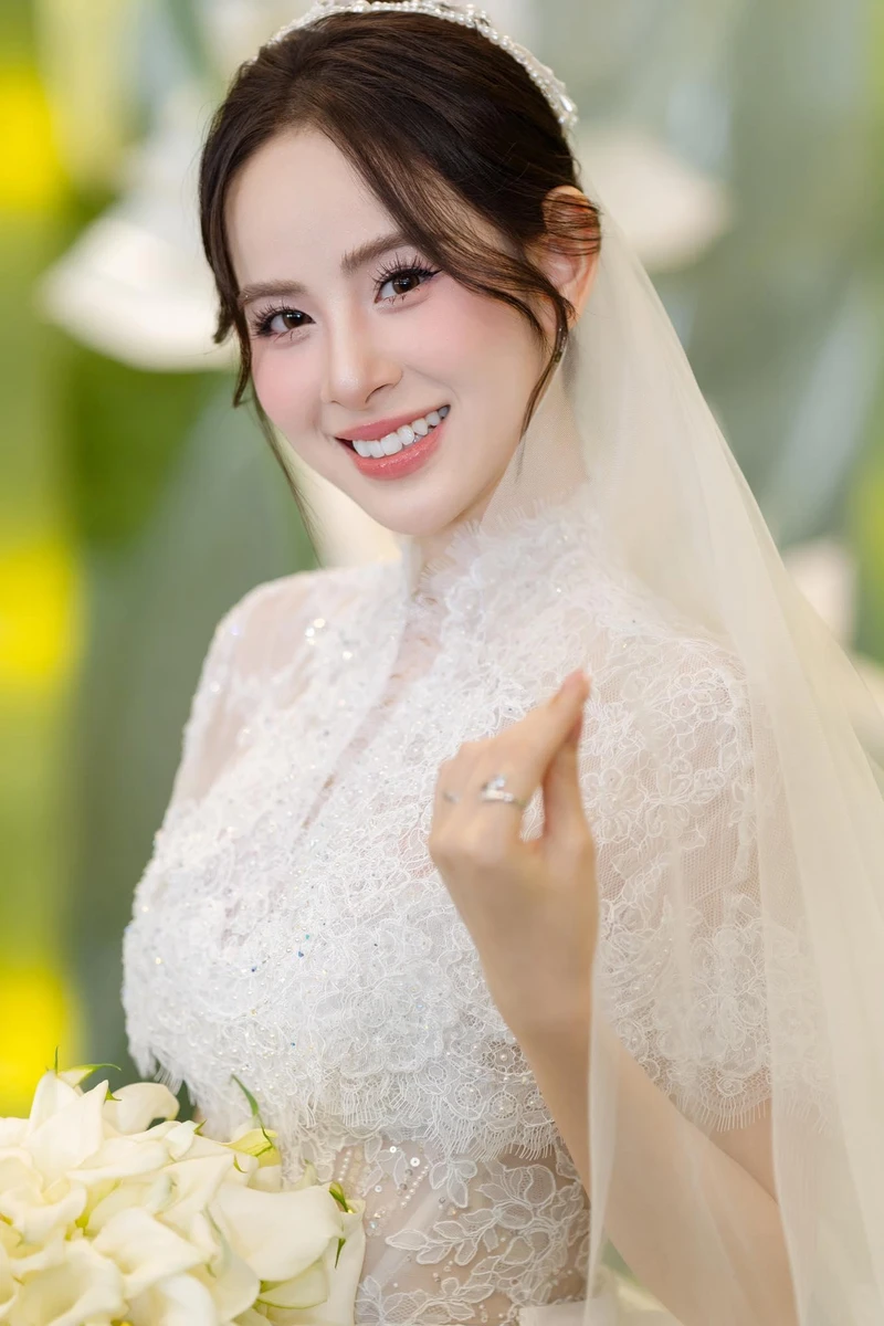 Cô dâu diện váy cưới với voan ren trắng cầm hoa cưới trắng