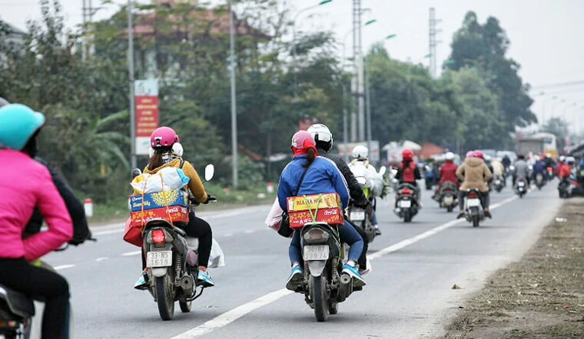 Mọi người di chuyển bằng phương tiện xe máy lưu thông đông đúc trên đường về quê ăn Tết