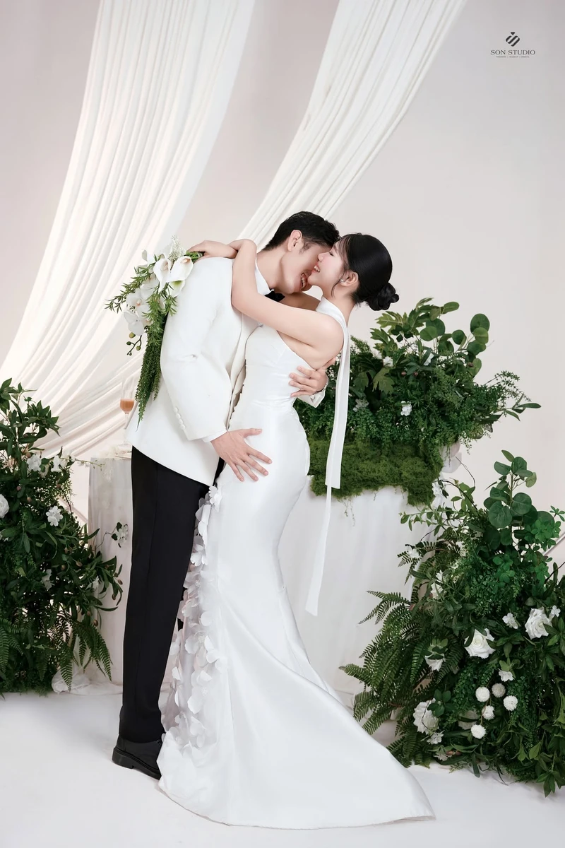 Váy cưới đuôi cá cổ yếm ôm dáng, cô dâu tạo dáng cùng chú rể trong studio