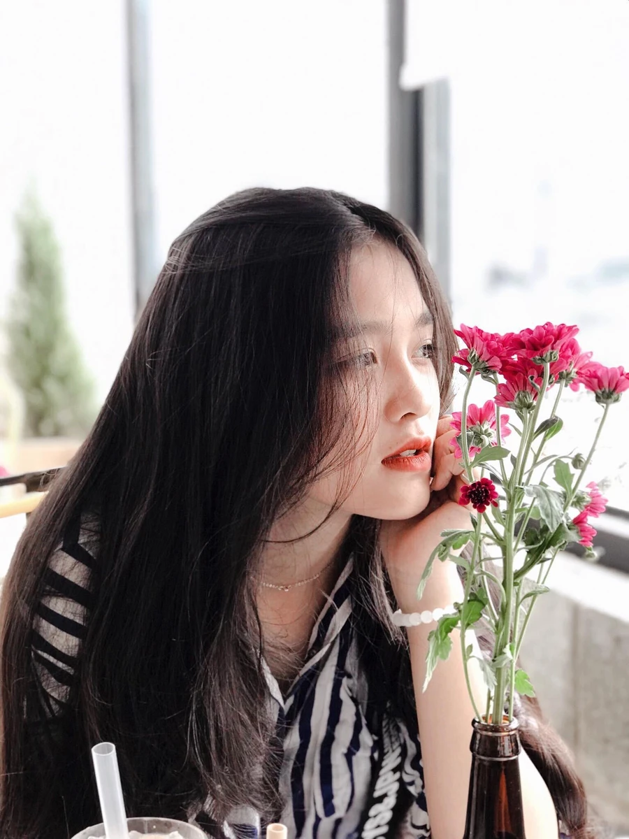 Hình ảnh cô gái dang dịu dàng ngồi bên cửa sổ