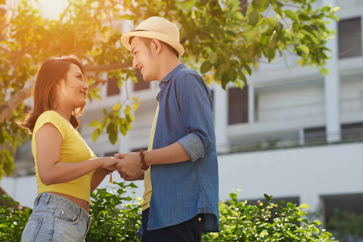 Cặp đôi nắm tay nhau dưới ánh nắng vàng và trao nhau ánh mắt dịu dàng