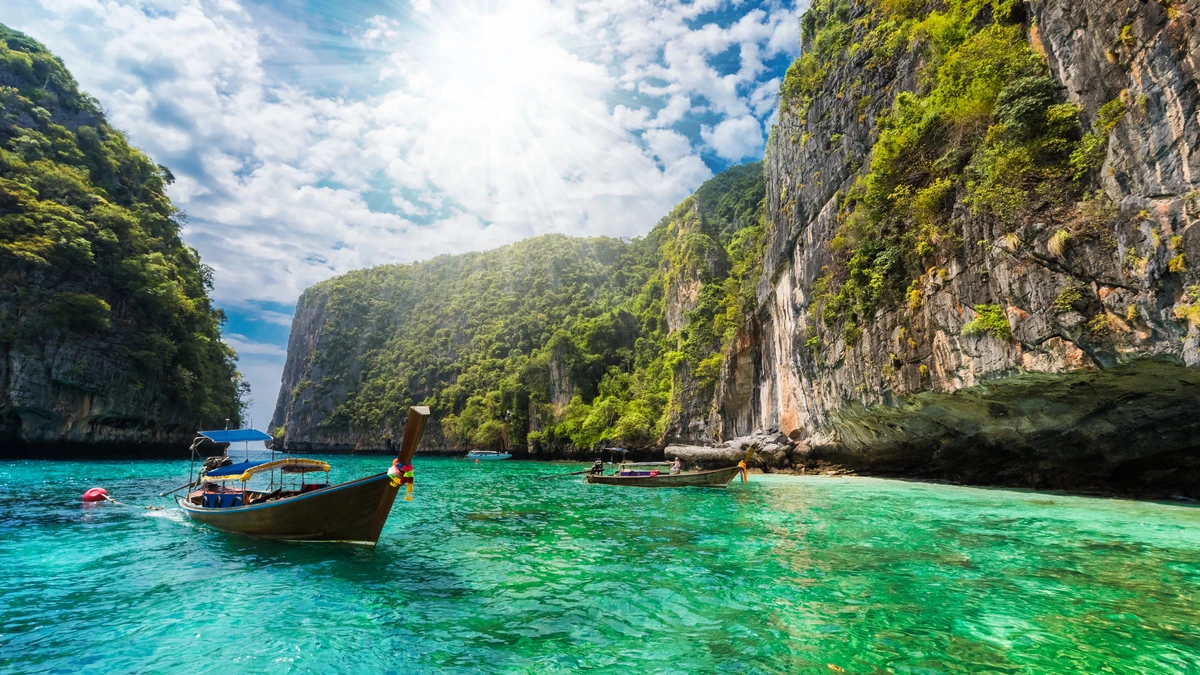Thuyền gỗ truyền thống di chuyển trên làn nước xanh trong tại vịnh Maya Bay, một trong những bãi biển nổi tiếng của Thái Lan