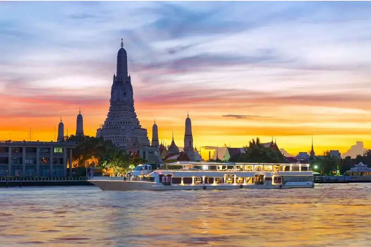 Thuyền du lịch trên sông Chao Phraya với khung cảnh chùa Wat Arun phía sau, biểu tượng nổi tiếng của Bangkok.