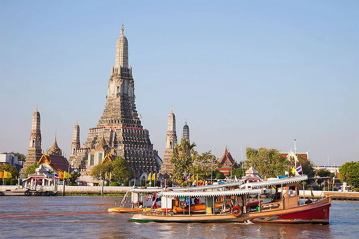 Thuyền du lịch trên sông Chao Phraya với khung cảnh chùa Wat Arun phía sau, biểu tượng nổi tiếng của Bangkok