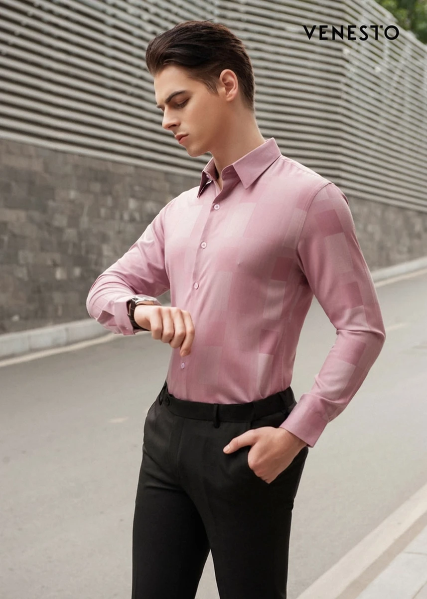Mẫu nam mặc áo sơ mi hồng tay dài, quần tây đen, đang xem đồng hồ